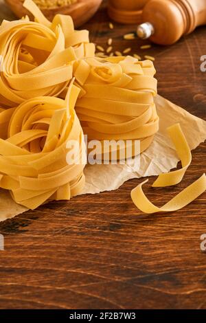 Tagliatelle fatte in casa in carta marrone su un vecchio sfondo di legno. Foto Stock