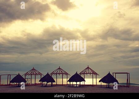 Vecchi e nuovi cottage sulla spiaggia in costruzione con nuvoloso & moody sky nel pomeriggio Foto Stock