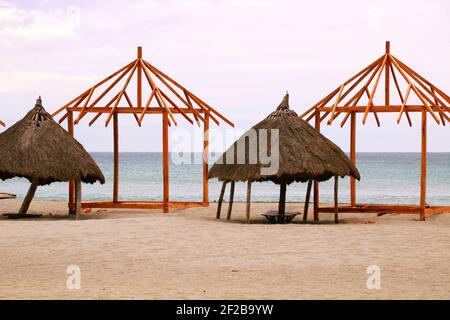 Vecchi e nuovi cottage sulla spiaggia in costruzione con nuvoloso & moody sky nel pomeriggio Foto Stock