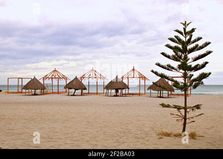 Vecchi e nuovi cottage sulla spiaggia in costruzione con nuvoloso & moody sky nel pomeriggio Foto Stock