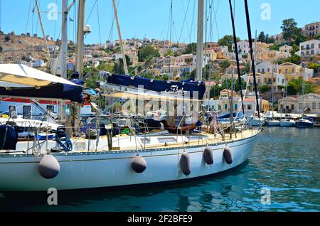 Paesaggio con barche a vela e architettura neoclassica nel porto dell'isola di Symi, Grecia Dodecanese. Foto Stock