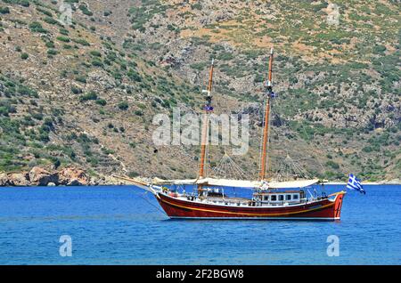 Paesaggio con una goletta tour in barca sulle acque del Mar Egeo meridionale nell'isola di Symi Dodecanese, Grecia. Foto Stock