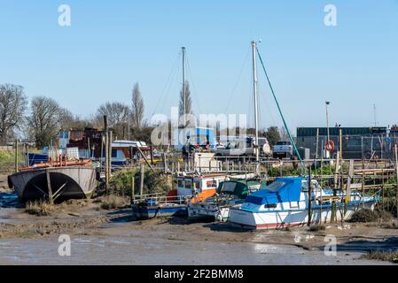 Fiume Roach a bassa marea vicino a Rochford e Stambridge, Essex, Regno Unito. Navi vecchie e in decadimento. Barche che si siedono sul fango vicino al cantiere. Barche Foto Stock