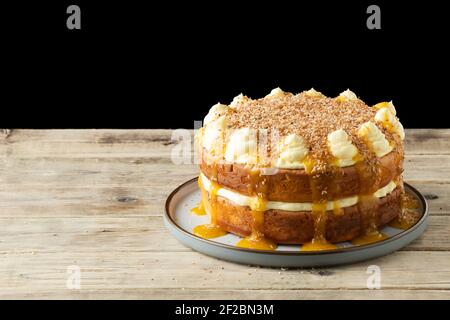 Una festa Mango, cocco e torta di yogurt. È composto da una ricetta di cottura Nadiya Hussain. La torta è ricoperta di polpa di mango e cocco tostato Foto Stock