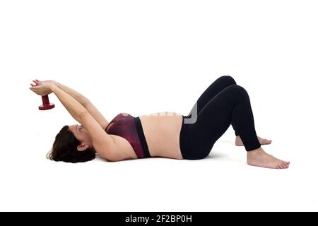 donna incinta che si esercita sul pavimento con manubri su bianco sfondo Foto Stock