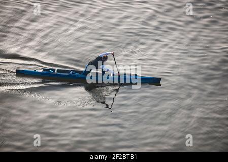 Praga, repubblica Ceca - 24 Febbraio 2021. Vista aerea del giovane uomo che naviga su una canoa blu in canoa sprint al tramonto Foto Stock