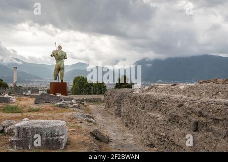 Rovine di Pompei con la scultura in bronzo di Igor Mitoraj - Daedalus, donata a Pompei. In lontananza-montagne e cielo nuvoloso Foto Stock