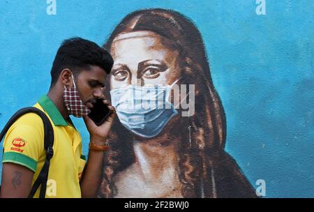 Mumbai, Maharashtra, India. 11 Marzo 2021. Un uomo che parla al telefono passa davanti a un graffito di Mona Lisa a Mumbai.nonostante il picco in casi di coronavirus nello stato di Maharashtra, la gente non aderisce alle linee guida fornite dal governo per seguire la distanza sociale, indossare maschera e utilizzare disinfettante. Credit: Ashish Vaishnav/SOPA Images/ZUMA Wire/Alamy Live News Foto Stock