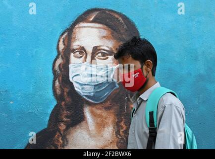 Mumbai, Maharashtra, India. 11 Marzo 2021. Un uomo che indossa una maschera facciale cammina oltre un graffito di Mona Lisa a Mumbai.nonostante il picco in casi di coronavirus nello stato di Maharashtra, la gente non aderisce alle linee guida fornite dal governo per seguire la distanza sociale, indossare maschera e utilizzare disinfettante. Credit: Ashish Vaishnav/SOPA Images/ZUMA Wire/Alamy Live News Foto Stock