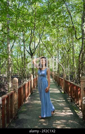 Bella ragazza che cammina attraverso la foresta di mangrovie in Asia. Foto Stock