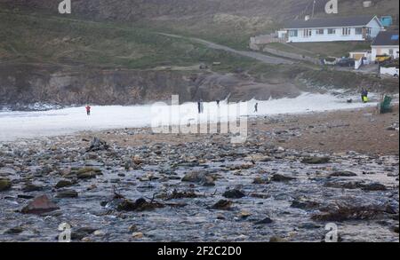 Porthtowan, Cornovaglia, 11 marzo 2021, a causa dei forti venti di 50 mph ci sono stati mari molto ruvidi in Porthtowan, Cornovaglia verso la fine di questo pomeriggio. La gente camminava sulla spiaggia nella schiuma di mare. La temperatura è di 8C, intervalli di sole con venti raffici. Credit: Keith Larby/Alamy Live News Foto Stock