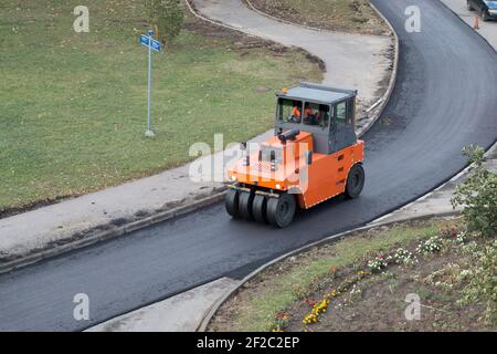 Compattatore a rulli durante il funzionamento. Processo di rinnovo della strada, compattazione dell'asfalto. Lavori di costruzione di strade, pavimentazioni in asfalto. Vista ad angolo alto Foto Stock