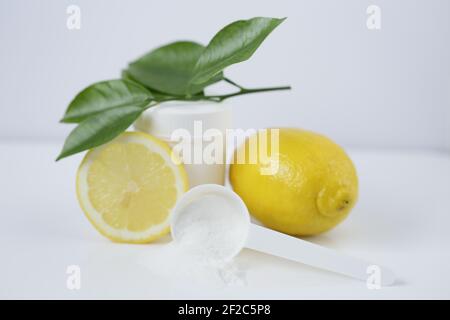 Polvere di vitamina C. vasetto bianco e cucchiaino di misurazione, polvere bianca di vitamina C e limoni in un taglio su uno sfondo chiaro.prevenzione di raffreddori e influenza. Un farmaco Foto Stock