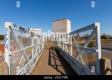 Stambridge Mill, sul fiume Roach ad est di Rochford. Mulino maremoto danneggiato dal fuoco e per lo più demolito, lasciando enormi sili. Passerella Foto Stock