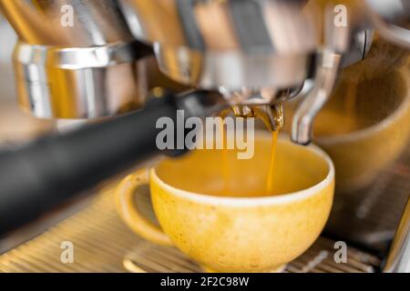 Preparazione di una bevanda espresso con una macchina da caffè professionale a casa, primo piano. Mettere a fuoco una tazza mentre si versa il caffè. Foto Stock