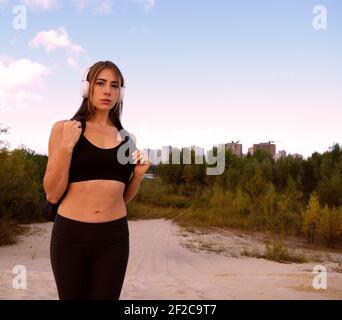 Giovane donna sportiva con cuffie e zaino all'aperto la campagna Foto Stock