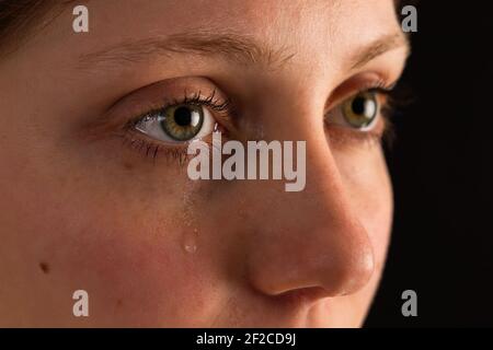 Faccia di femmina infelice in lacrime da vicino nelle tenebre. Foto Stock