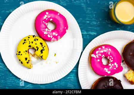 Un piatto di ciambelle. Festa sulla veranda estiva. Ciambella morso su una stalla. Una ciambella mezza mangiata. Foto Stock