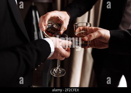 Riunione di affari. Gli uomini tengono bicchieri di whisky. Festa degli uomini. Mani con una bevanda di alcool. Foto Stock