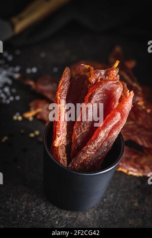 Carne di pollo essiccata. Gustosa carne a scatti in tazza nera. Foto Stock