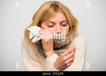 Ragazza in sciarpa tenere termometro e tessuto da vicino. Misurare la temperatura. Concetto di febbre. Rompere i rimedi febbre. Temperatura sintomi influenzali. La donna si sente Foto Stock