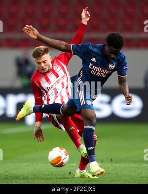 Oleg Reabciuk di Olympiacos (a sinistra) e Bukayo Saka di Arsenal combattono per la palla durante il sedici round della UEFA Europa League, prima tappa allo stadio di Karaiskakis, in Grecia. Data immagine: Giovedì 11 marzo 2021. Foto Stock