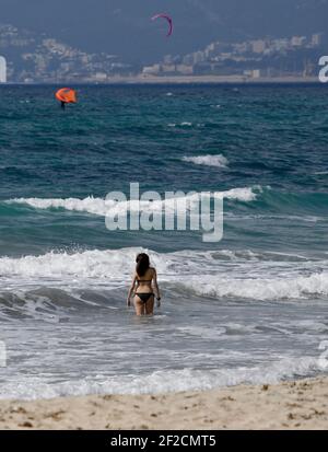 Palma, Spagna. 11 Marzo 2021. Una donna va per una nuotata nelle onde alla spiaggia di Arenal. I tour operator tedeschi sperano di riportare i turisti a Maiorca dalle vacanze di Pasqua. Credit: Clara Margais/dpa - ATTENZIONE: I nomi dei tubi sono stati pixelati per motivi legali/dpa/Alamy Live News Foto Stock