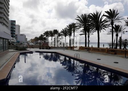 Palma, Spagna. 11 Marzo 2021. Gli alberi di palma si riflettono nella piscina di un hotel chiuso sulla spiaggia di Arenal. I tour operator tedeschi sperano di poter riportare i turisti a Maiorca dalle vacanze di Pasqua. Credit: Clara Margais/dpa - ATTENZIONE: I nomi dei tubi sono stati pixelati per motivi legali/dpa/Alamy Live News Foto Stock