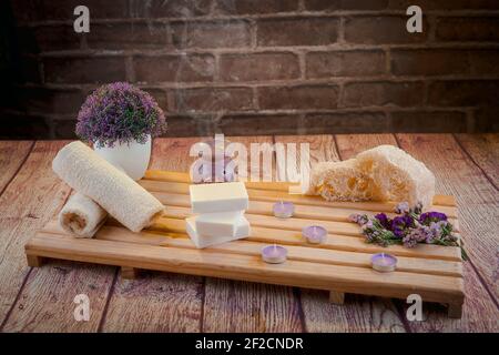 Bella composizione termale con saponi naturali con candele profumate e accessori da bagno in un ambiente romantico per un concetto di pulizia. Foto Stock