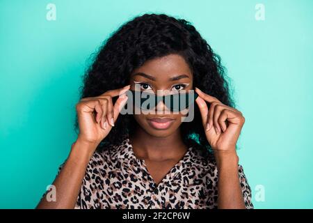 Foto di donna seria decollo specifiche indossare occhiali da sole leopardo stampa camicia isolato turchese sfondo colore Foto Stock