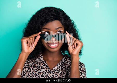 Foto di signora curiosa take off occhiali da sole aspetto spazio vuoto indossa stampa leopardata camicia isolato colore teal sfondo Foto Stock