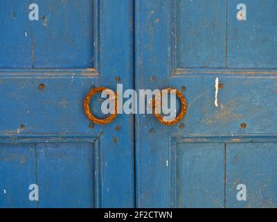 Una porta in legno, vintage, completamente blu con pomelli arancioni su ogni porta. Foto Stock