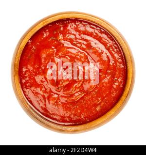 Arrabbiata salsa in una ciotola di legno. Salsa piccante di pomodoro italiana per la pasta, a base di pomodori, aglio e peperoncini rossi secchi, cotti in olio d'oliva. Foto Stock