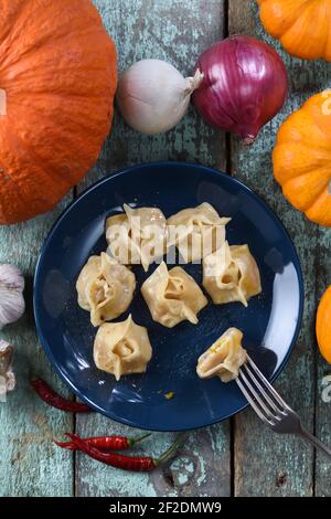 Piatto vegetariano sano. pumpkin manti, tradizionali gnocchi al vapore dell'Asia centrale decorati con zucche grezze, cipolle e pepe sopra la vista Foto Stock