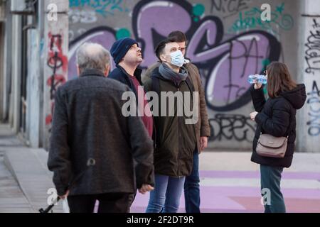 BELGRADO, SERBIA - 21 FEBBRAIO 2021: Giovane uomo che indossa una maschera respiratoria che guarda sopra il cielo nella strada di Belgrado, durante il coronav Foto Stock