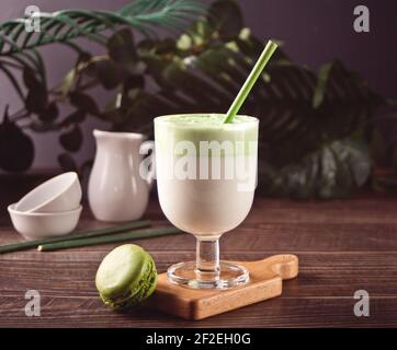 Dalgona Matcha latte, tè verde matcha con panna montata e pianta sullo sfondo. Foto Stock