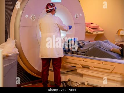 Palo alto, California - 21 febbraio 2021: Anziano uomo sdraiato per la scansione MRI con infermiere che lo prepara. Foto Stock