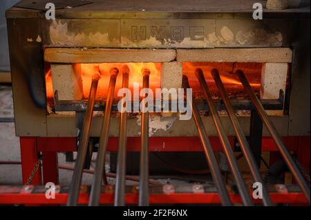 Fusione del vetro in forno ad alta temperatura. Soffianti in vetro in attesa di lavoratori. Primo piano degli interni di vetreria. Foto Stock