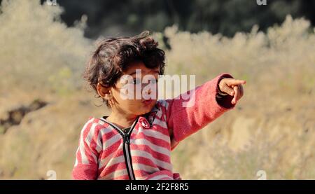 Un ragazzino di origine indiana si vede a guardare lontano dalle dita e dalla mano. Concetto per i bambini di oggi futuro, ricordi d'infanzia, sorriso Foto Stock