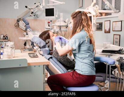 Giovane donna che riceve cure dentali in clinica moderna. Foto Stock