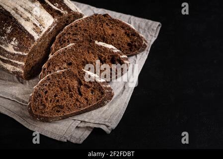 Pane affettato di segale. Impasto artigianale pane scuro su fondo nero Foto Stock