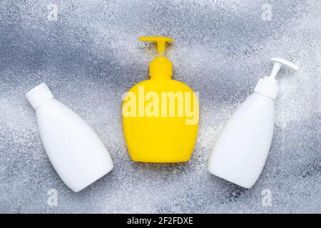 Flacone giallo con detergente, sapone liquido. Pancetta bianca. Set di flaconi in plastica con dispenser su sfondo grigio. Lozione pompa. Con igiene personale Foto Stock