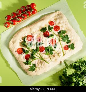 Focaccia, pizza, pane piatto con verdure, sfondo verde di colore brillante Foto Stock