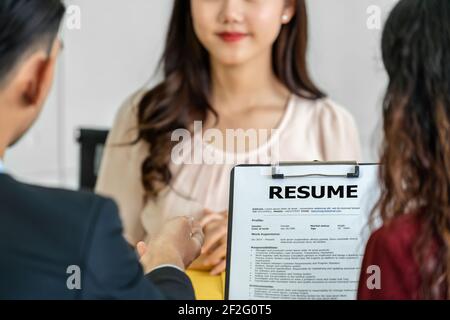 Primo piano Resume in due mani manager tenere quando discutere su Il suo resume con il movimento di felicità sopra giovane donna asiatica laureata intervistare in riunione Foto Stock