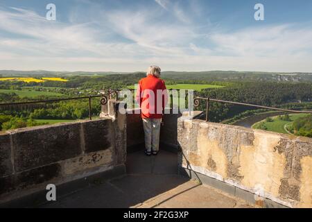 Vista posteriore di una donna anziana alla Fortezza di Koenigstein in una giornata di sole. Sta guardando sopra il paesaggio della valle dell'Elba, Foto Stock