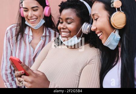 Giovani donne ispaniche divertirsi insieme in città mentre Uso del telefono cellulare - Focus principale sulla ragazza africana Foto Stock