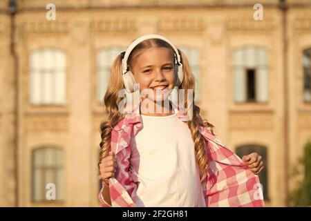 ragazza felice scuola indossare auricolari. bambina stile casual all'aperto. vacanza primaverile appena iniziato. la sua playlist estiva preferita. bambino ascoltare musica. sorridente bambino ascoltare audio libro. Foto Stock