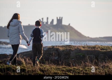 Due bambini che camminano a Dunstanburgh, Northumberland, Regno Unito Foto Stock