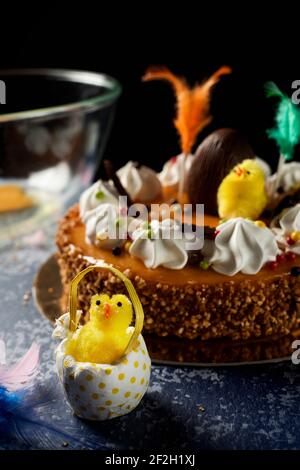 Primo piano di un pulcino peluche in un uovo finto e una torta mona de pascua, mangiato il lunedì di Pasqua in Spagna, ornato con un pulcino morbido, un uovo di cioccolato e. Foto Stock