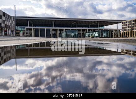 12 marzo 2021, Brandeburgo, Schönefeld: Terminal 1 dell'aeroporto della capitale Berlino il Brandeburgo "Willy Brandt" (BER) si riflette in una pozza. Nel pomeriggio si svolge una riunione del Consiglio di sorveglianza della Flughafen Berlin-Brandenburg GmbH. L'argomento principale è le future esigenze finanziarie dell'azienda. La società di gestione conta sulla riduzione parziale del debito da parte degli stati di Berlino, Brandeburgo e governo federale. Foto: Patrick Pleul/dpa-Zentralbild/ZB Foto Stock